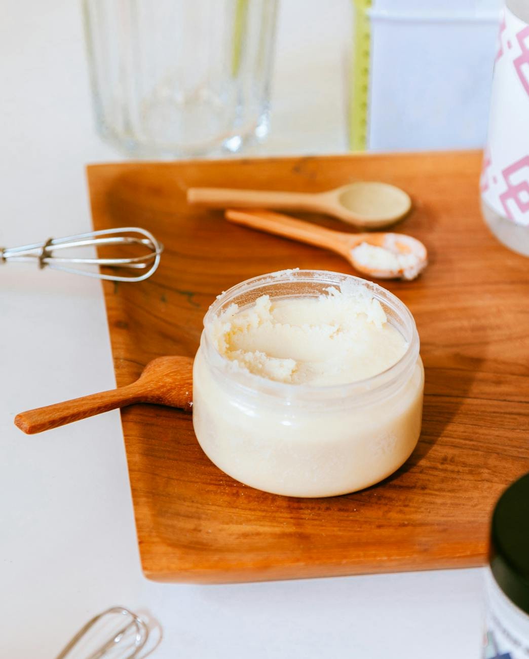 close up of a container with a creamy product standing on a wooden cutting board